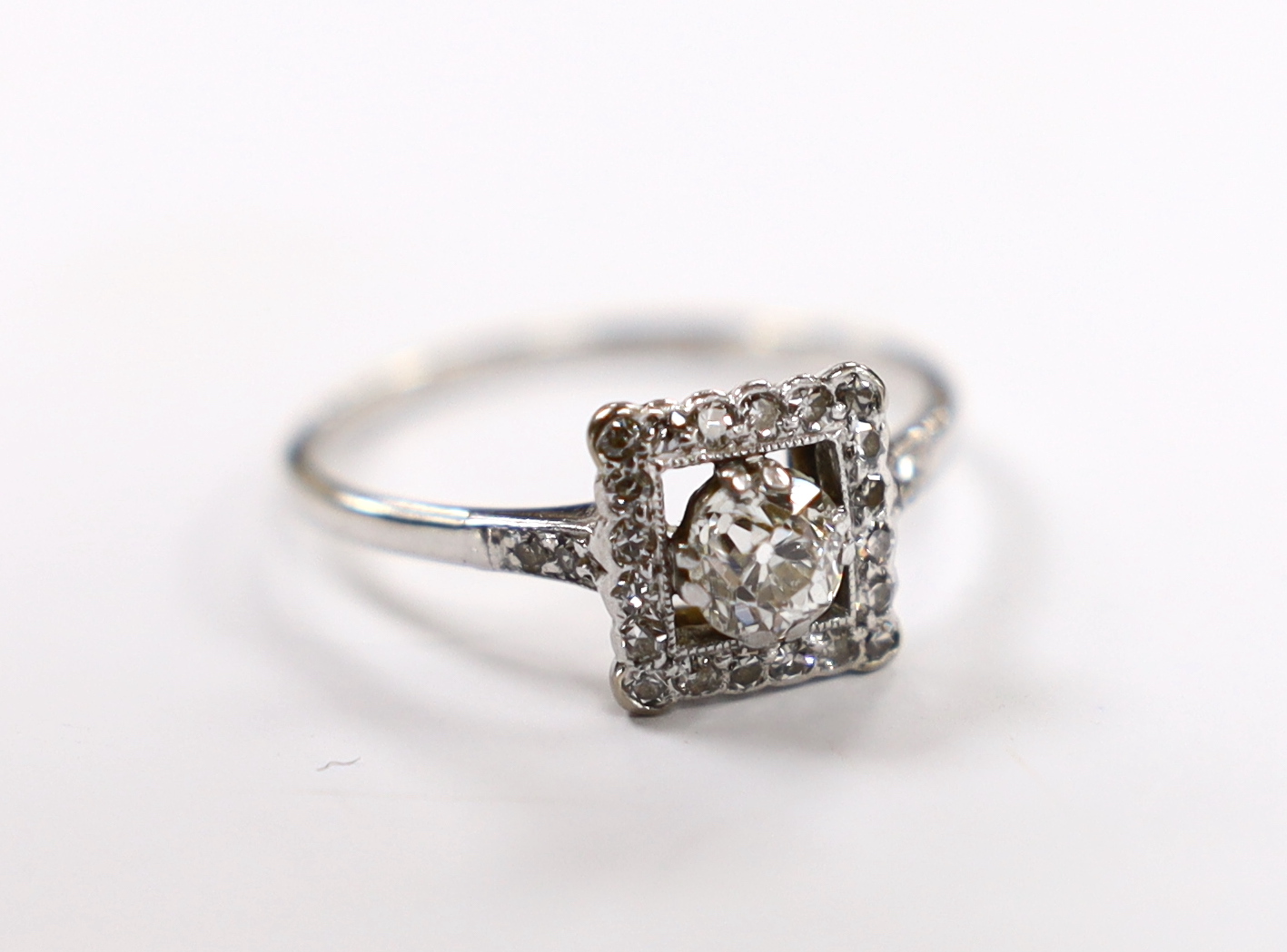 A 1940's 18ct white metal and single stone diamond ring, with diamond set square border and diamond set shoulders, size Q/R, gross weight 2.7 grams